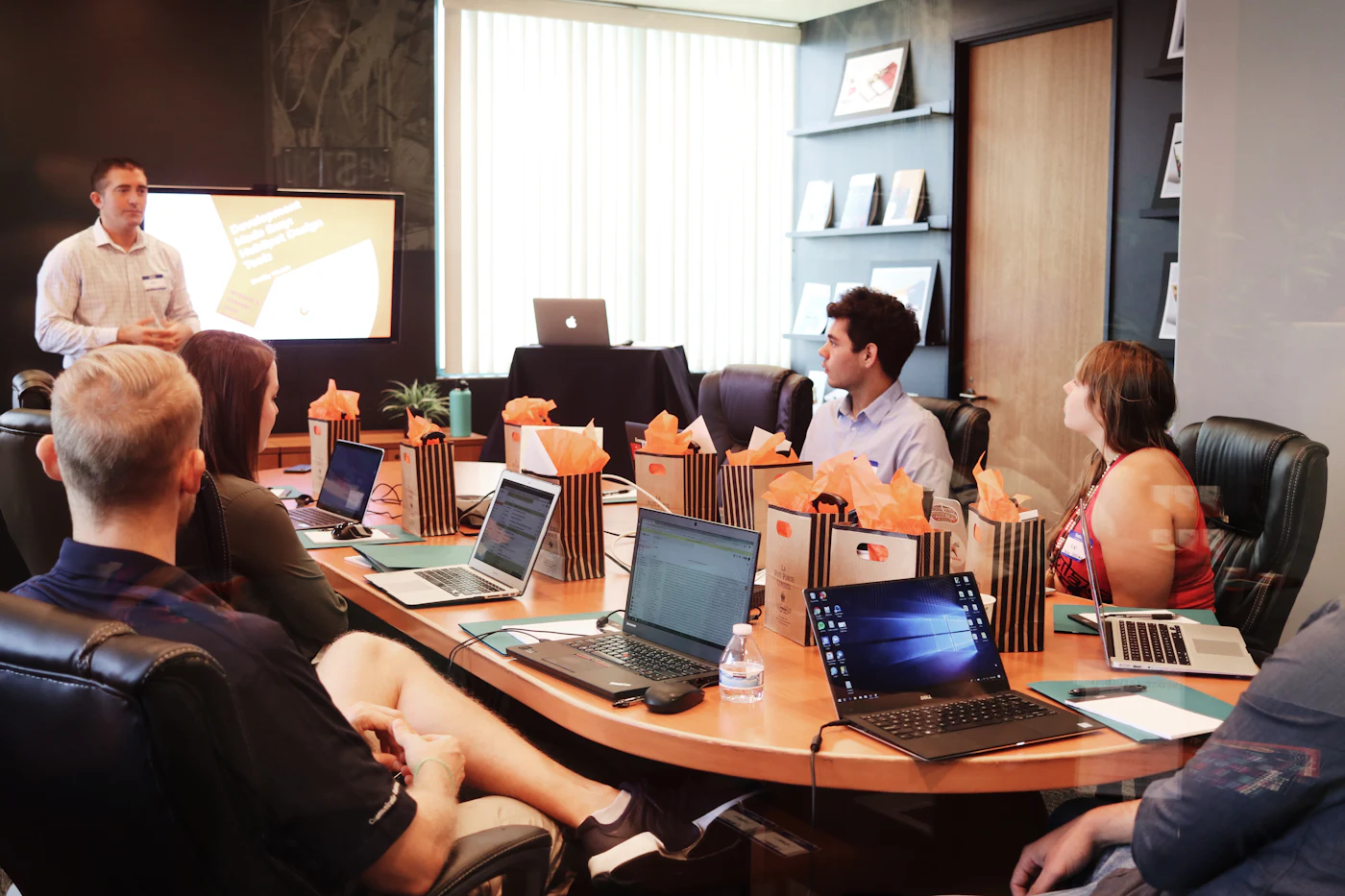 Equipe de RH em reunião de planejamento de benefícios corporativos, com notebooks sobre a mesa